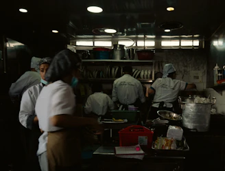 A busy catering kitchen with chefs preparing fresh ingredients and packaging meals.