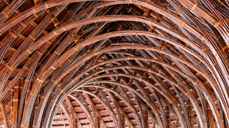 Artisan hands skillfully bundling bamboo and cane with natural rope, forming elegant curved structures.