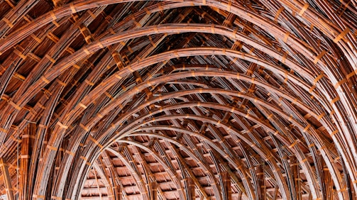 Intricately woven arches made from bamboo create a textured, layered pattern that gives the impression of depth and repetition. The natural material and craftsmanship showcase a blend of traditional techniques with a modern architectural style.