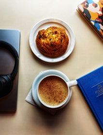 Close-up of headphones and a notebook filled with conversation topics beside a steaming cup of coffee.