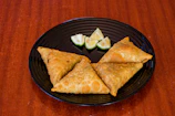 Close-up of a golden, crispy samosa with steam rising.