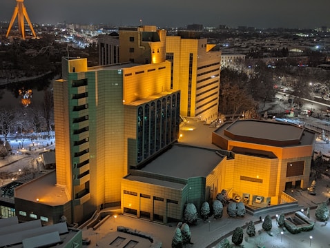 Night view of a commercial complex illuminated with warm golden lights and sleek gray surfaces.