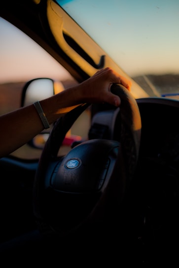 A friendly driving instructor guiding a relaxed student during a practical driving lesson on a sunny day.