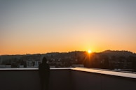 Model showcasing a minimalist hoodie on a city rooftop at sunset.