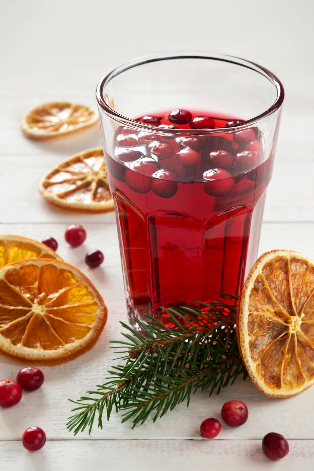 a glass of red liquid with oranges and oranges