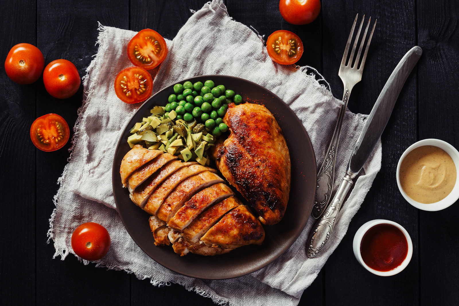 Blanc de poulet rôti et doré, servi avec des petits pois et des tomates