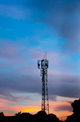 A vibrant radio tower emitting colorful waves against a sunset sky.