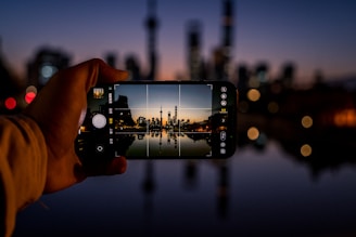Person using a mini smartphone outdoors with a cityscape in the background.