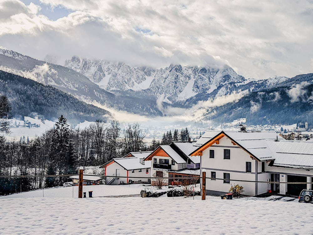 um grupo de edifícios em uma área nevada com montanhas ao fundo