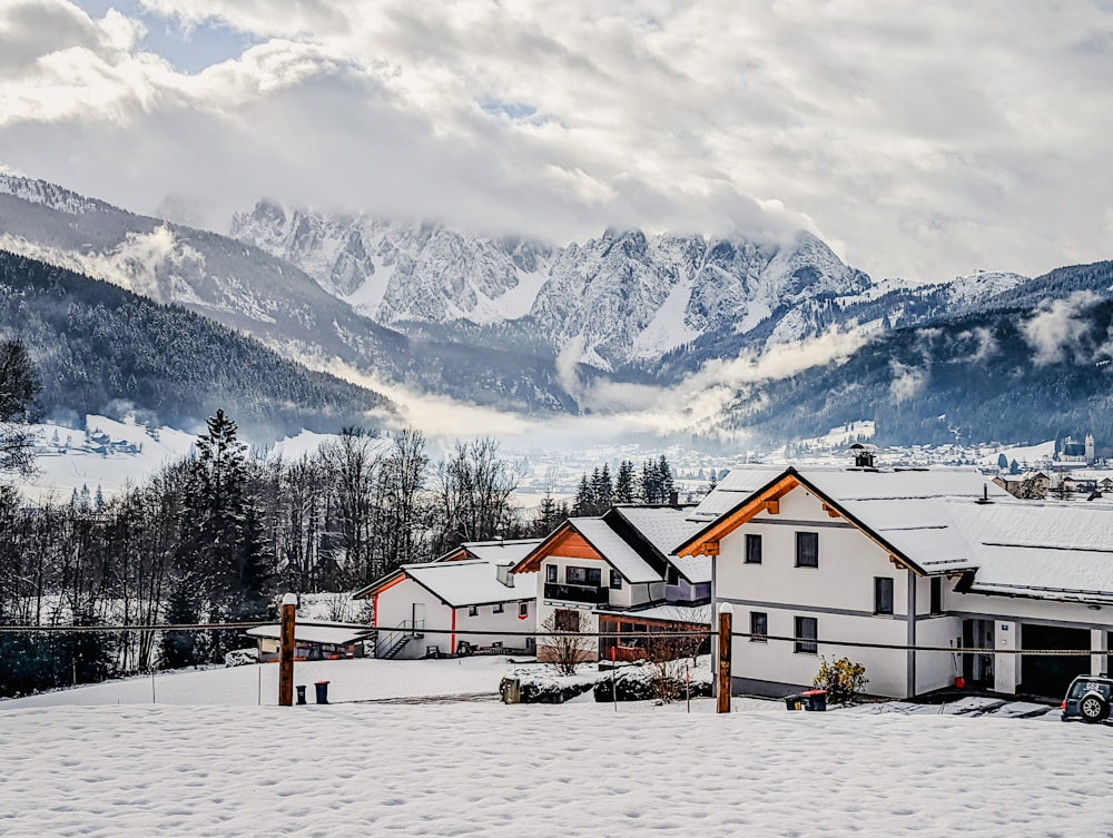 a group of buildings in a snowy area with mountains in the background