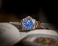A blue and gold luxury wristwatch resting on an open book