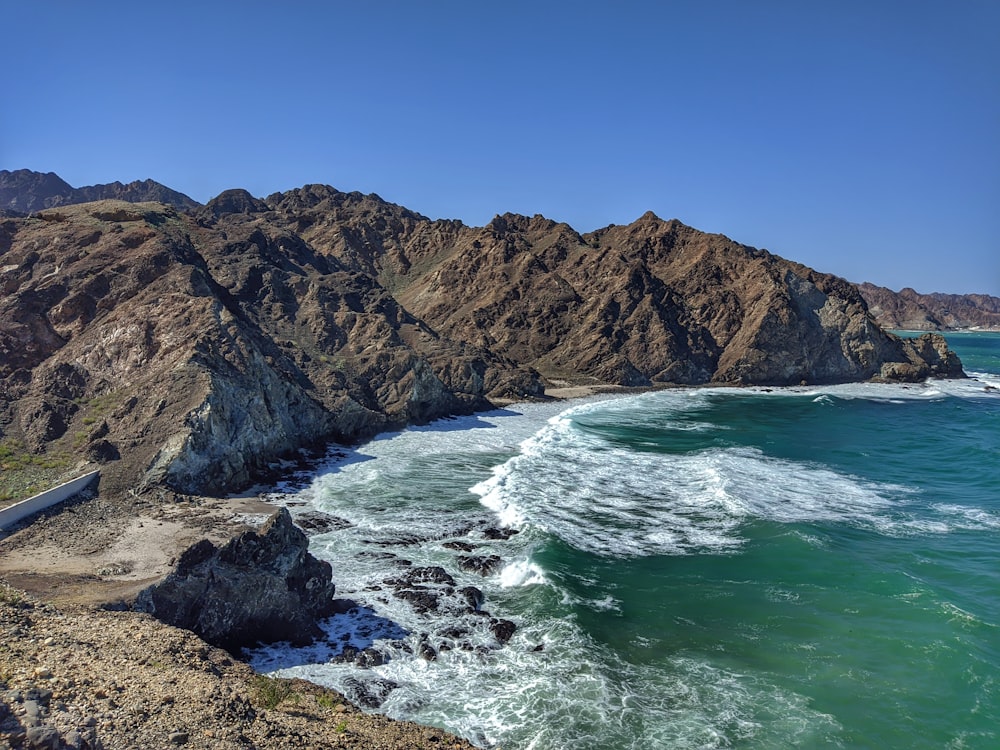 a rocky beach with a body of water and a large cliff