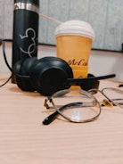 Modern blue light blocking glasses on a desk next to a laptop and coffee cup.