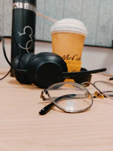 A sleek pair of smart glasses resting on a modern desk with a laptop and coffee cup nearby.