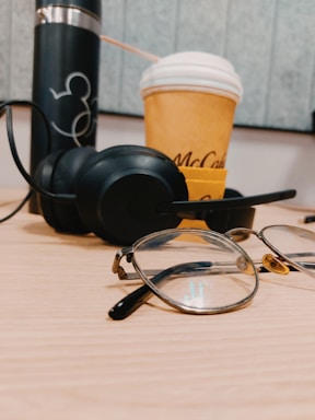 A sleek pair of Mentraos smart glasses resting on a modern desk beside a laptop and a cup of coffee.