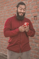 Portrait of Ali Raza smiling warmly, standing in front of a display of mobile phones.