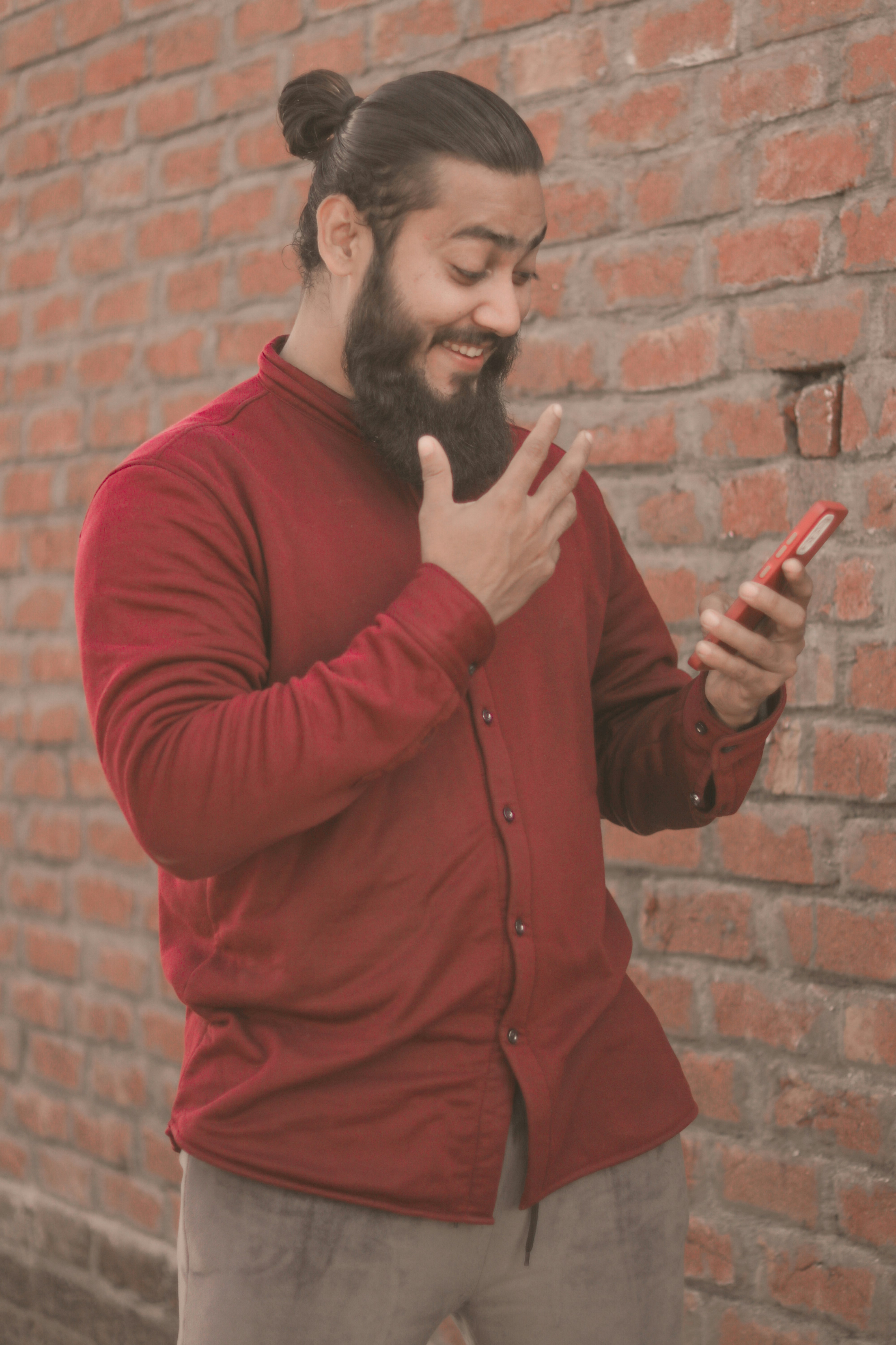 a man with a beard pointing at a cell phone