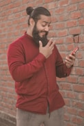 a man with a beard pointing at a cell phone