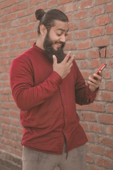 a man with a beard pointing at a cell phone