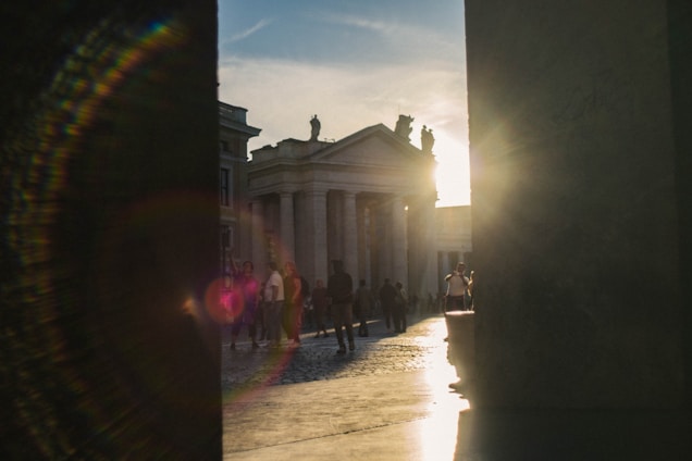 Pilgrims walking together towards a historic Catholic sanctuary during sunset.