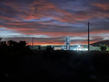 A warm sunset behind a group of retirees standing proudly in front of a historic power plant.