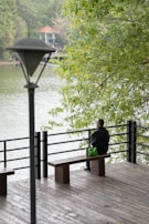 A solitary figure sitting on a bench overlooking a calm lake at sunset.