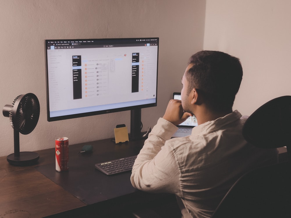 a man sitting at a desk looking at a computer screen