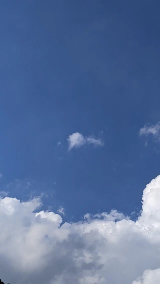 A charming illustration of a boy sitting on a fluffy white cloud, gazing at a bright blue sky filled with soft, drifting clouds.