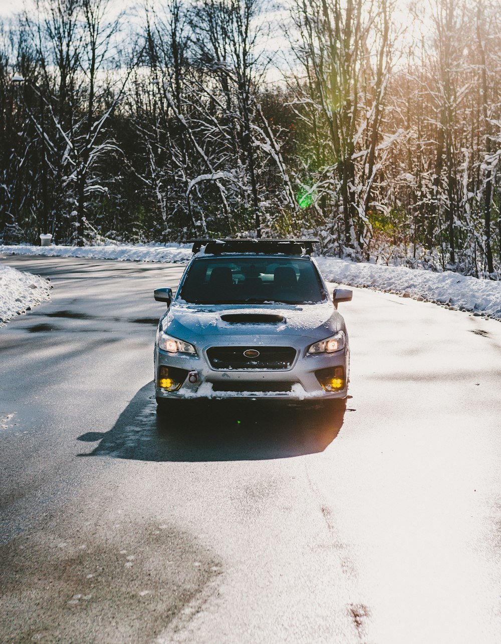 a car parked on a road with snow on the side