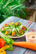 A vibrant photo of a veggie wrap on a wooden table with fresh ingredients around.