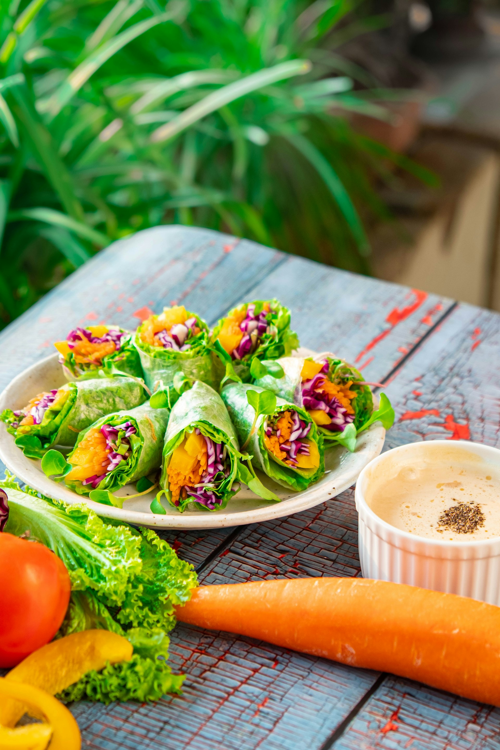 A vibrant shot of freshly made wraps filled with colorful veggies and herbs, laid out on rustic wooden table.