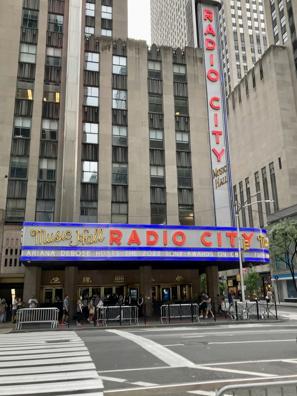 a large building with a sign on it with Radio City Music Hall in the background
