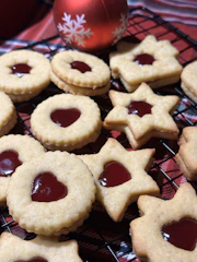 Artisan Linzer cookies with vibrant raspberry filling, arranged on a rustic wooden board.