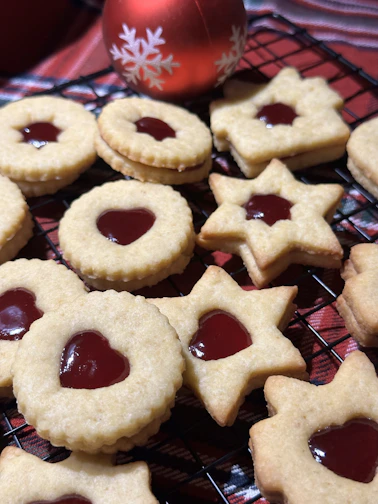 Artisan Linzer cookies with vibrant jam centers arranged on a rustic wooden board.