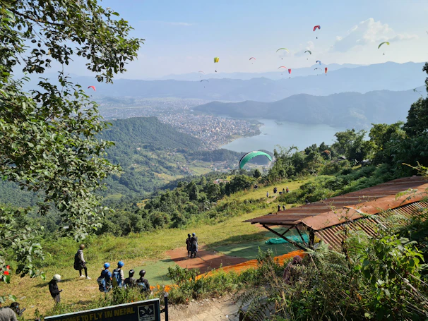 A group of paragliders launching from the ridge with the blue lagoon visible in the distance