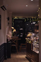 Warmly lit café corner with cups of coffee, plates of cake slices, and delicate floral decorations.