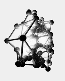 A complex structure composed of numerous connected spheres and rods, forming a three-dimensional geometric shape. The arrangement resembles a molecular or atomic model, with a mix of dark and light elements creating a striking contrast.