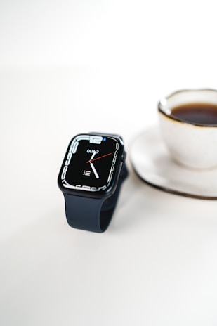 A sleek smartwatch glowing softly on a wooden table beside a cup of coffee.