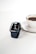A sleek watch resting on a wooden table beside a cup of coffee.