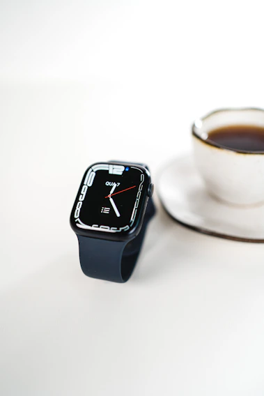 A sleek android smartwatch glowing softly on a wooden desk beside a coffee cup.