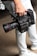 A person is holding a professional RED digital cinema camera with a large lens and multiple attachments. The camera has visible branding, buttons, and handles, indicating it is designed for high-quality film production. The person is wearing light-colored jeans and sneakers.