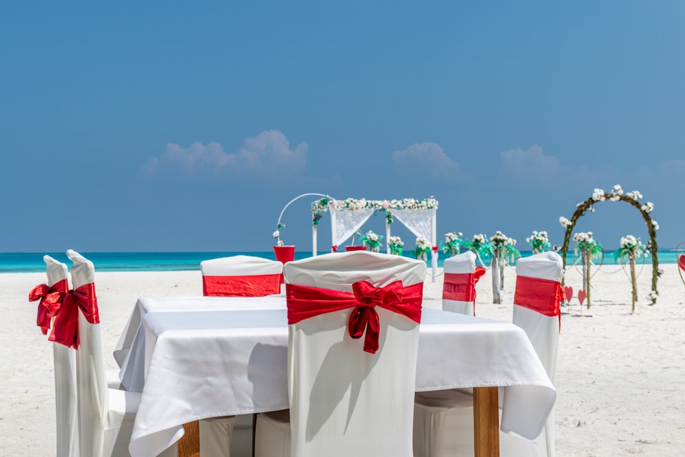 a group of white tables and chairs on a beach
