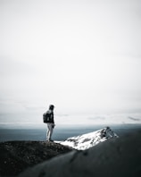 A lone traveler standing on a mountain ridge overlooking the snow-capped peaks of Himachal Pradesh at sunrise.