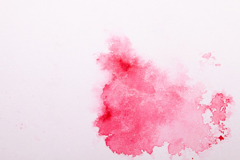 A soft, abstract watercolor splash featuring various shades of pink on a white background. The colors blend and diffuse gently with some areas appearing more saturated while others are lighter, creating a sense of fluidity and delicateness.