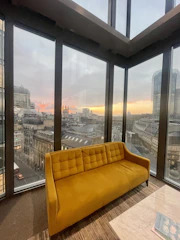 Luxurious living room with sleek modern furniture and large windows overlooking a cityscape at sunset.