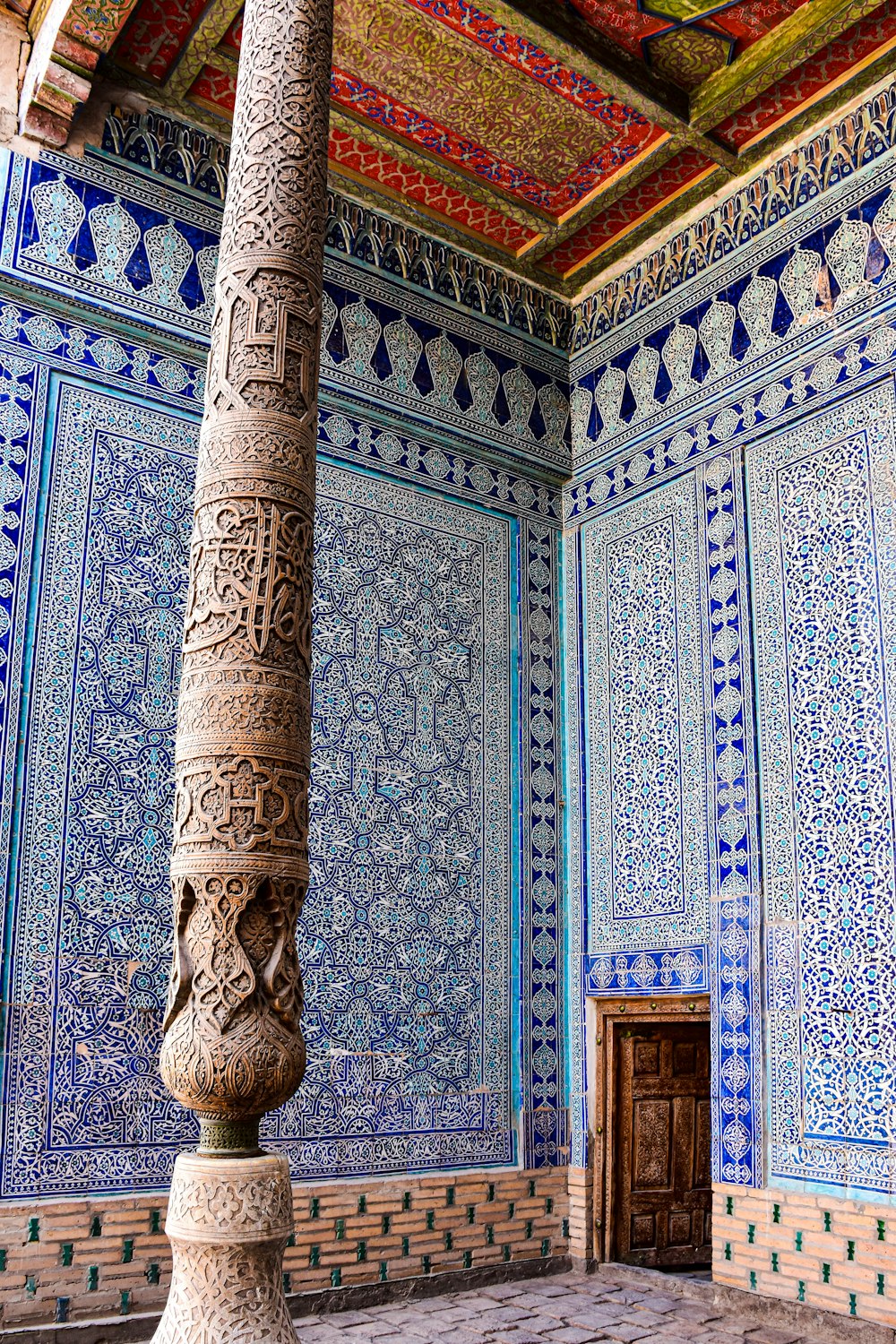 a pillar in front of a wall with a design on it