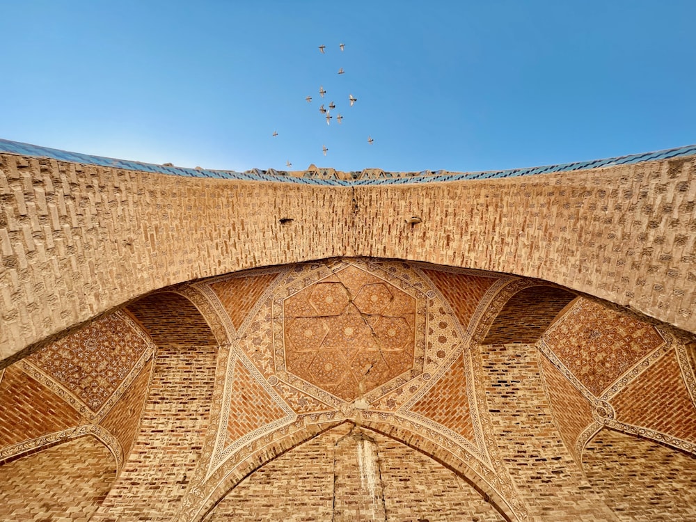 a large stone building with many birds flying in the sky