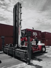 A large industrial machine being carefully loaded onto a shipping container for global delivery.