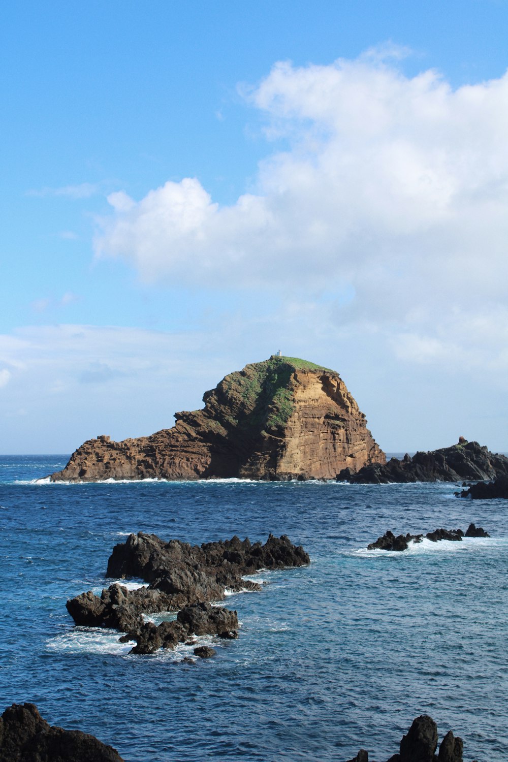a rocky island in the ocean with Roque de Garachico in the background