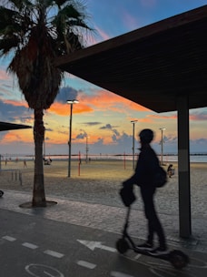 A vibrant electric scooter speeding along a coastal boardwalk at sunset.